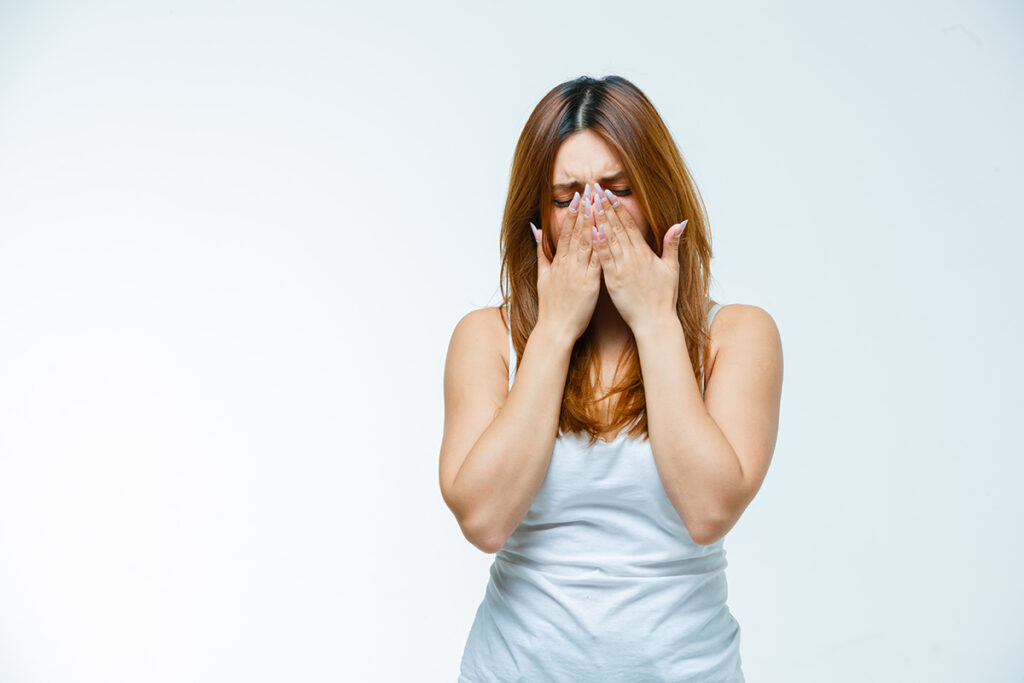 young female holding hands on mouth while crying in white blous